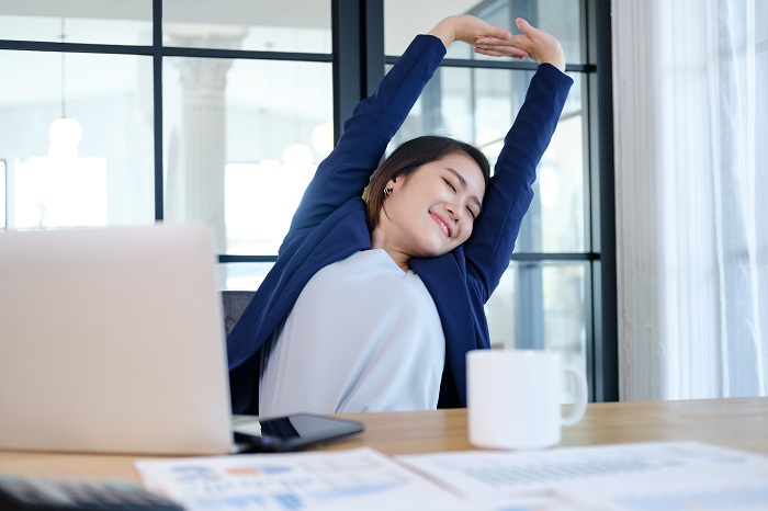 Woman twisting her body while taking a break from sitting in office